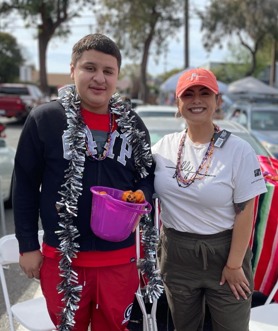 A teenager and an adult dressed festively smiling and posing for a photo