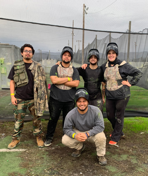 Group of people posing for a group photo on a paintball court